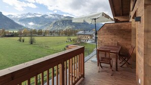 A wooden deck with a table and chairs, overlooking a green field and mountains. - Premium # 1A mit Sauna by Interhome (Uttendorf)