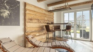 A room with a log wall, a glass door leading outside, and a bar area with chairs. - Premium # 1A mit Sauna by Interhome (Uttendorf)