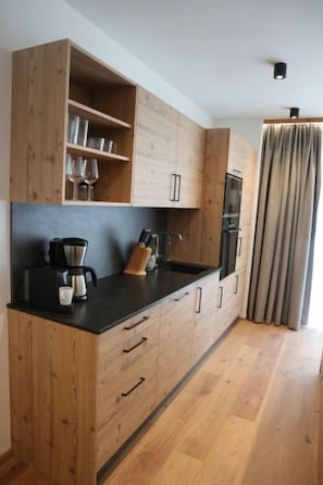 Una cocina moderna con armarios de madera, encimera negra y horno empotrado.