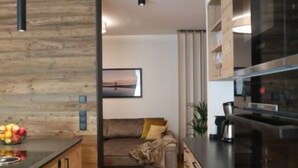Eine moderne Küche mit Holzausstattung, einem eingebauten Ofen und einem Essbereich mit einer Couch.