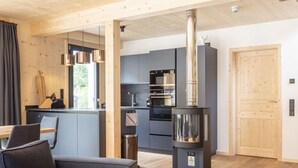 Een moderne keuken met donkere kastjes, roestvrijstalen apparatuur en een centraal geplaatste schoorsteen.