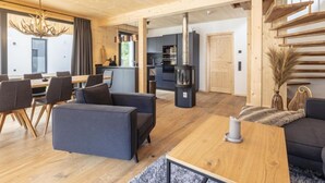 Een modern interieur met een eethoek, banken, een open haard en een keuken op de achtergrond.