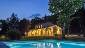 Uma casa de dois andares com piscina na frente.