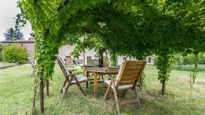 An outdoor dining area with a wooden table and chairs under a large tree. - Rent house in the valley of Menotre (Pale)