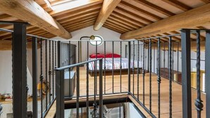 A high-ceilinged room with exposed wooden beams and a metal railing. - Rent house in the valley of Menotre (Pale)