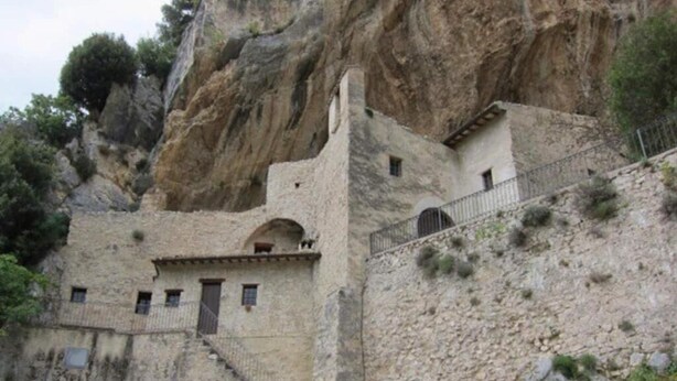 A stone building with a staircase leading up to a door, surrounded by rocky terrain and sparse vegetation. - Rent house in the valley of Menotre (Pale)