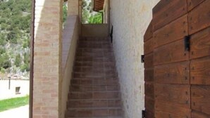 A staircase leading to a wooden door, with a stone wall on one side and a clear view of the outdoors. - Rent house in the valley of Menotre (Pale)