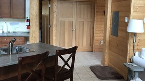 Un interior de madera con cocina, mesa de comedor, sillas y una cama.