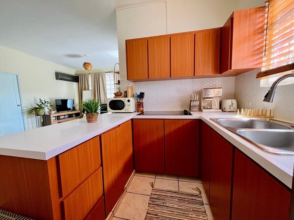A compact kitchen with wooden cabinets, a microwave, a toaster, and a sink.