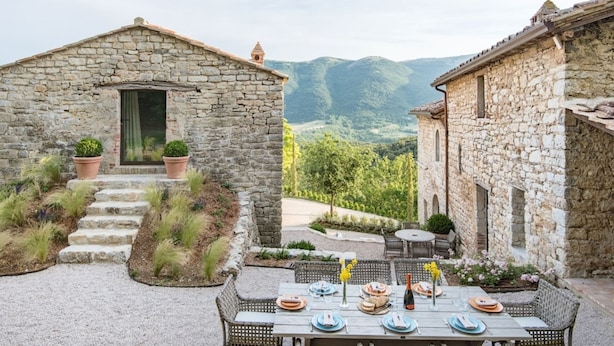 A stone building with a small entrance and steps leading up to it, surrounded by greenery and a mountainous backdrop. - Luxury villa inside a splendid estate (Perugia)