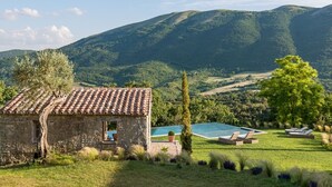 A stone building with a tiled roof, a swimming pool, and lounge chairs. - Luxury villa inside a splendid estate (Perugia)