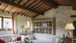 Una habitación acogedora con pared de piedra, techo de madera y sofá blanco con cojines a rayas.