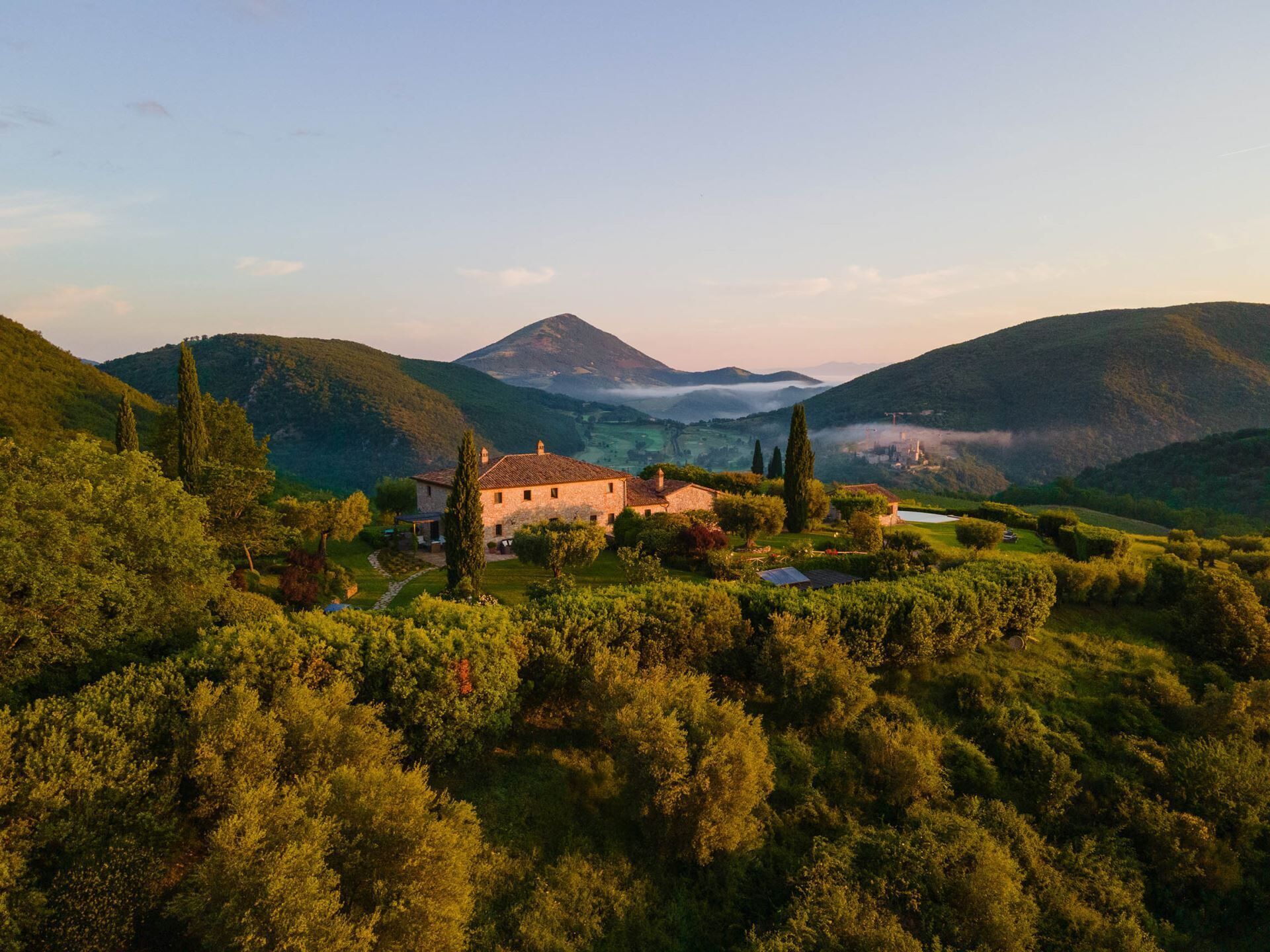 Une maison en pierre avec un jardin et une vue sur une vallée et des montagnes.