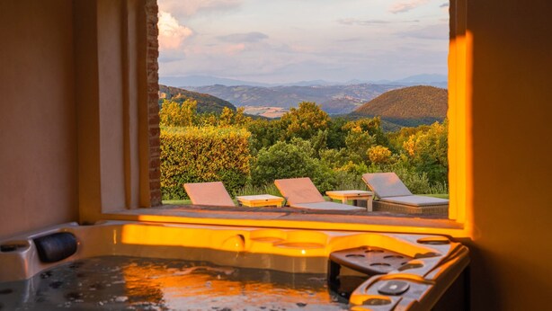 Ein Whirlpool mit Blick auf einen angelegten Garten und Berge.