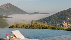 Ein Infinity-Pool mit Blick auf eine gebirgige Landschaft und ein Dorf.