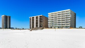 A beachfront hotel with multiple floors, a staircase leading to the beach, and a clear blue sky. - Perdido Skye Beach Front Condo | King Bed/Bunk Quarters | Gulf Front Views | Private Balcony | Pool (Pensacola)