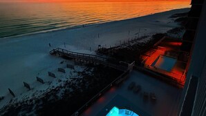 An aerial view of a beach resort with a swimming pool, a wooden deck, and a view of the ocean at sunset. - Perdido Skye Beach Front Condo | King Bed/Bunk Quarters | Gulf Front Views | Private Balcony | Pool (Pensacola)
