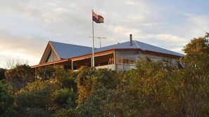 Ein modernes Haus mit einer gut sichtbaren Flagge an einem Fahnenmast, umgeben von dichtem Grün.
