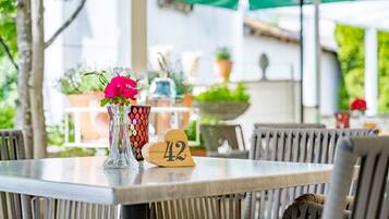 A dining table with a number 42 sign, a vase with flowers, and wicker chairs.