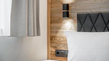 Une chambre d’hôtel moderne avec une tête de lit en bois, une table de chevet et une fenêtre avec des rideaux.