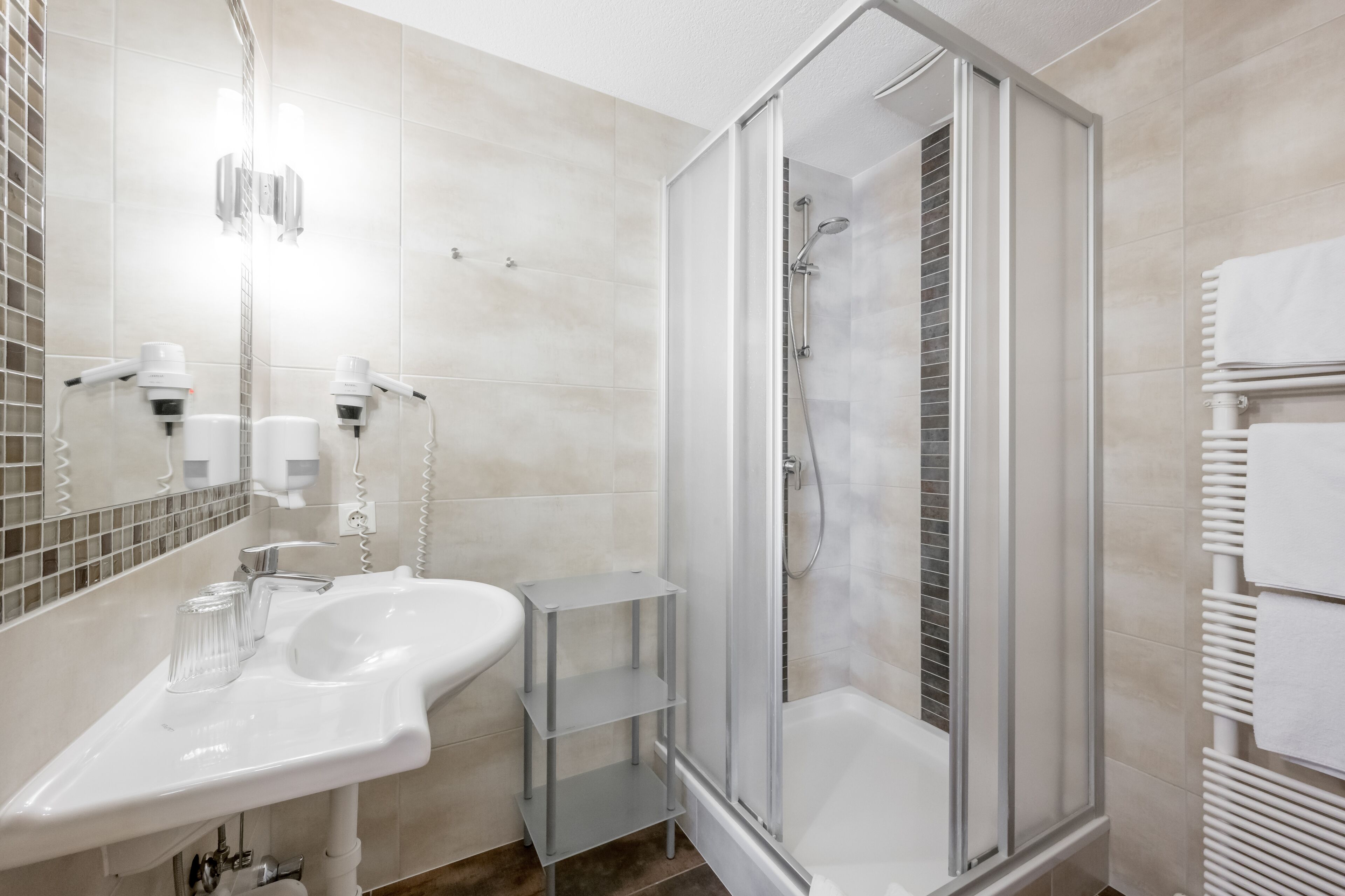 A modern bathroom with a glass-enclosed shower, a white sink, and a mirror.