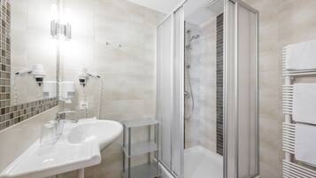 A modern bathroom with a glass-enclosed shower, a white sink, and a mirror.