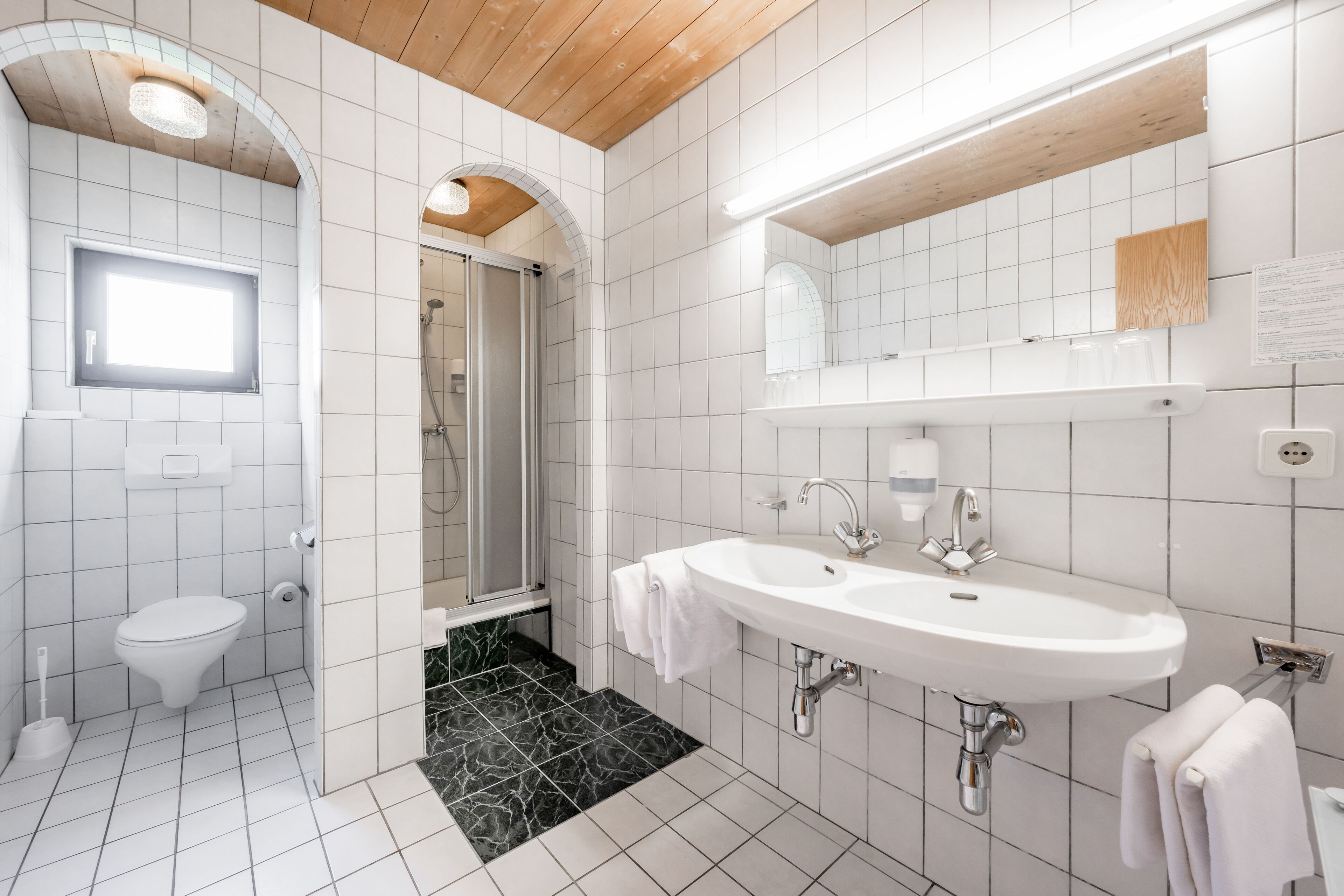 A modern bathroom with a white sink, mirror, and toilet.
