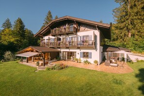 A two-story chalet with a balcony, a covered patio, and a well-maintained lawn.