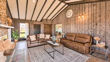 Un salon rustique avec des murs en bois, des canapés en cuir, une table basse et une horloge au mur.