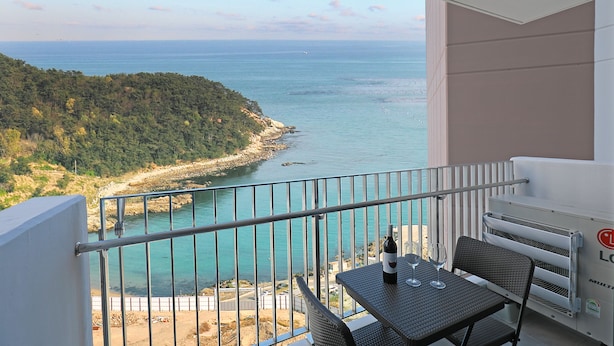 Un balcon avec vue sur la mer, une table avec une bouteille et un verre, et un appareil de climatisation.