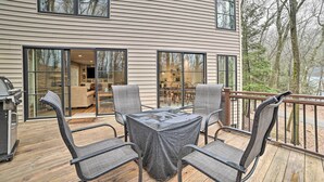 A deck with a covered table and chairs, a grill, and a view of the house and trees. - 2 Mi to Tunnel of Trees: Home w/ Furnished Deck (Harbor Springs)