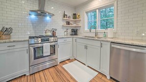 A modern kitchen with white cabinetry, stainless steel appliances, and a window providing natural light. - 2 Mi to Tunnel of Trees: Home w/ Furnished Deck (Harbor Springs)