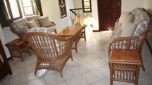 A living room with wicker furniture, a wooden coffee table, and a sofa.