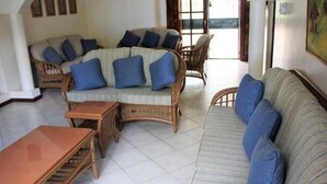 A living room with wicker furniture, including a sofa and chairs, and a small wooden table.