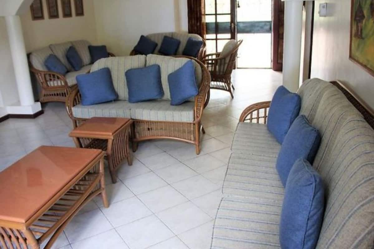 Ein Wohnzimmer mit Korbmöbeln, darunter eine Couch und Sessel, sowie ein kleiner Holztisch.
