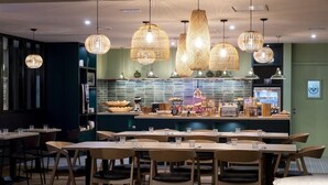 A restaurant with multiple tables and chairs, a counter with food items, and hanging wicker lamps. - L Hotel By Joa Saint Paul Les Dax (Saint-Paul-les-Dax)