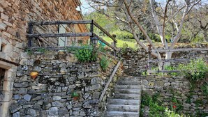 Eine Steintreppe führt zu einem Gebäude mit einer rustikalen Steinmauer und einem hölzernen Geländer.