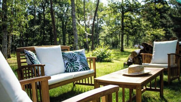 An outdoor seating area with wooden furniture and a hat on a table. - In the heart of nature, property 15 minutes from Chateau de Chambord! (La Ferté-Saint-Cyr)