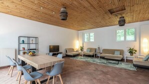 A spacious living area with a wooden ceiling, a dining table with chairs, a sofa, and a TV. - In the heart of nature, property 15 minutes from Chateau de Chambord! (La Ferté-Saint-Cyr)