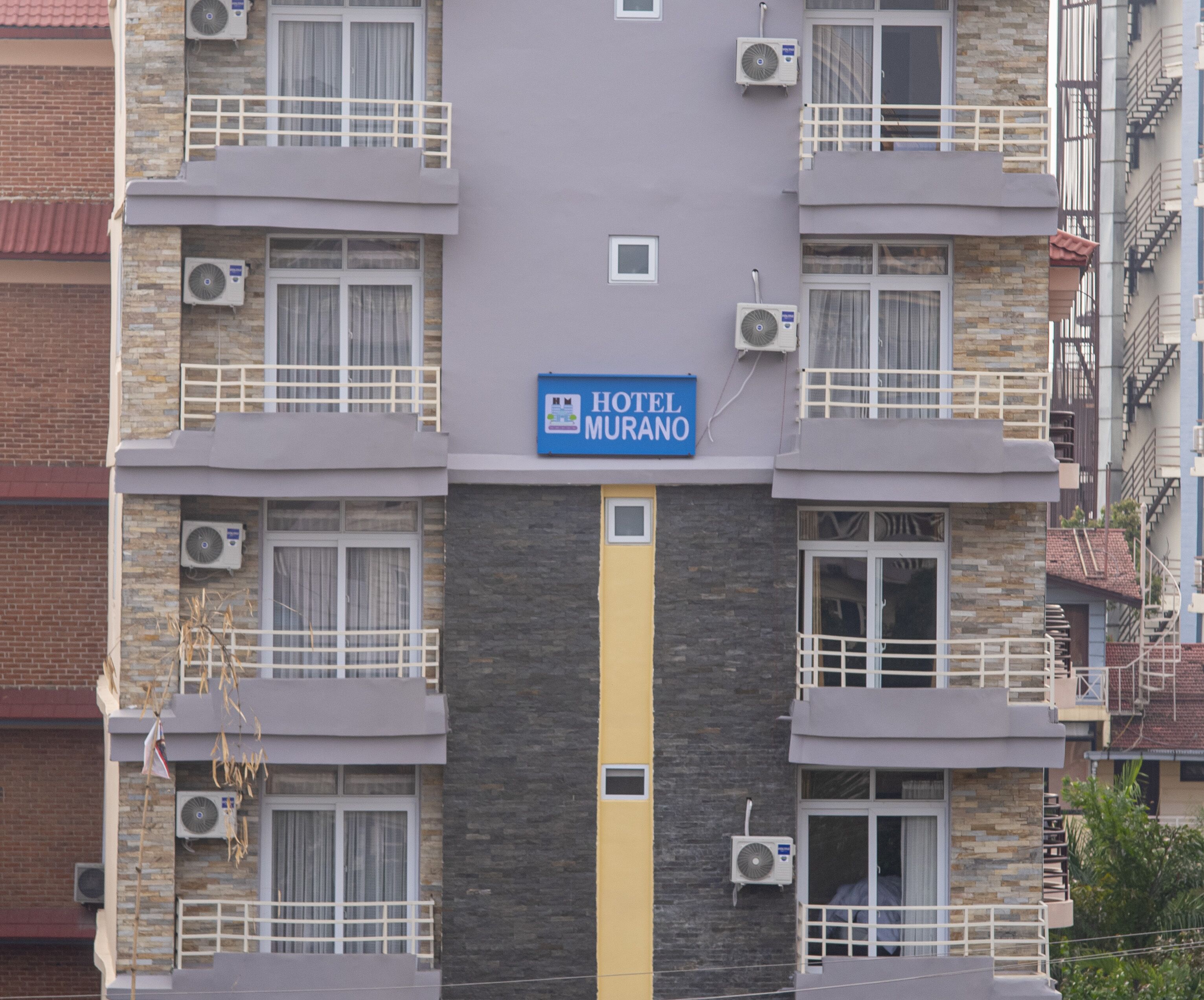 Un edificio de hotel de varios pisos con un letrero que dice "HOTEL MURANO".