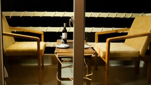 Una habitación con dos sillones, una mesita con una botella de vino y una guirnalda de luces.