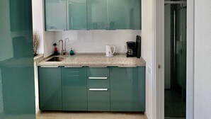 A modern kitchen with teal cabinets, a granite countertop, and a built-in oven. - Luxury Condo Sea View Large Terrace BenalBeach (Benalmádena)