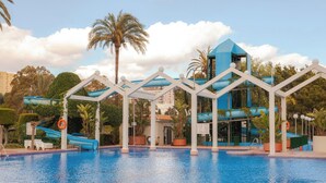 A swimming pool with a water slide and a blue building structure in the background. - Luxury Condo Sea View Large Terrace BenalBeach (Benalmádena)
