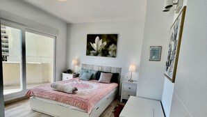 A modern bedroom with a large bed, a nightstand, a dresser, and a wall-mounted lamp. - Luxury Condo Sea View Large Terrace BenalBeach (Benalmádena)
