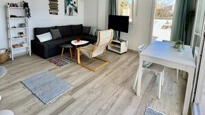 A modern living room with a sofa, a coffee table, a chair, a TV, and a dining table. - Luxury Condo Sea View Large Terrace BenalBeach (Benalmádena)