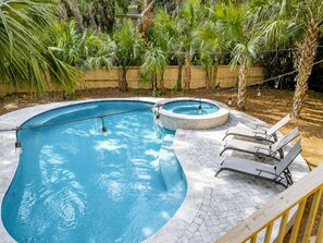 Una piscina con hidromasaje, rodeada de una terraza de madera y palmeras.
