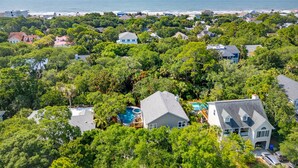 Área residencial com casas cercadas por vegetação exuberante, piscina e vista para o oceano.