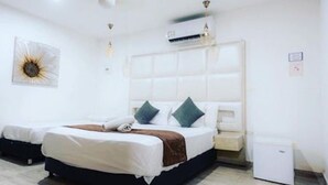 Een slaapkamer met een bed, nachtkastjes, een wandairconditioner en een plafondventilator.