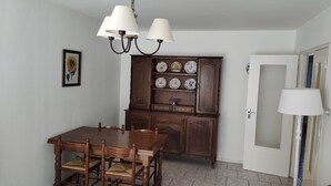 Un coin repas avec une table et des chaises en bois, un buffet orné d’assiettes décoratives et une porte avec une fenêtre.