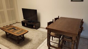 Un salon avec une table à manger en bois, un téléviseur posé sur un meuble et une petite table basse.